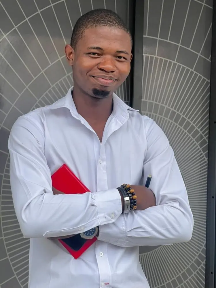 Olaitan Adebayo smiling, holding a red notebook