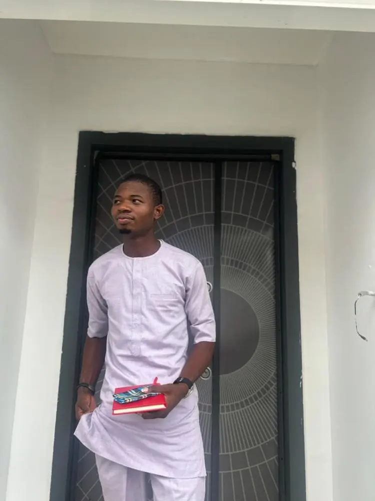 Olaitan Adebayo in a white kaftan, holding a red book